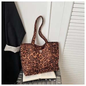 Close-up of leopard print canvas tote bag with bear patch on a travel suitcase