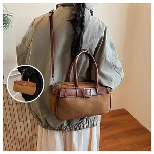 Detail of vintage brown suede bucket bag with leather trim and adjustable shoulder strap