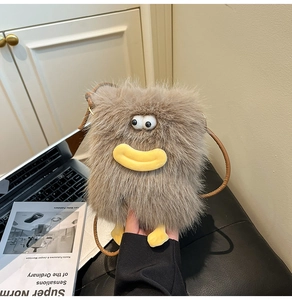 Detail of a brown plush monster crossbody bag featuring large 3D eyes and funny yellow lips