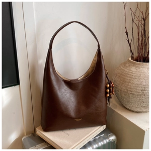 Détail d'un sac hobo en cuir PU marron foncé avec gland en perles de bois et texture souple