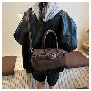 Detail of dark brown suede bucket bag with leather belt buckle and silver hardware