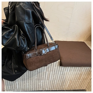 Detail of suede and leather patchwork brown bucket bag with vintage metal buckle