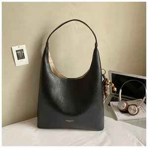 Détail du sac cabas en similicuir noir avec logo doré et pendentif vintage en perles de bois