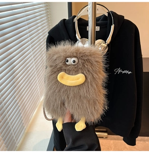 Detail of a brown fuzzy monster crossbody bag with large eyes and yellow duck beak