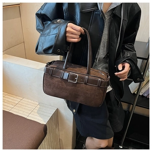 Detail showing the brown suede texture, leather strap decoration, and silver buckle of the bag