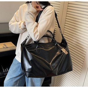 Vue détaillée du grand sac cabas noir avec finition brillante et bandoulière réglable