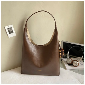 Détail d'un grand sac hobo marron avec breloques en perles de bois sur un bureau moderne