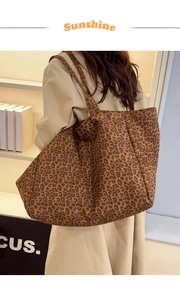 Detail view of a large leopard print tote bag being carried by a model on her shoulder