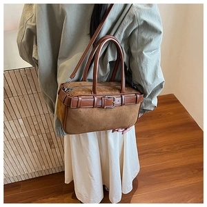 Detail of brown suede bucket bag featuring leather strap and adjustable top handle