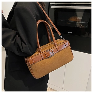 Brown suede bucket bag with leather straps and metal buckle details on model