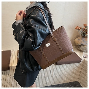 Détail du grand sac cabas léopard avec plaque logo en métal et longues bandoulières