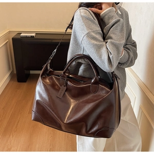 Sac cabas marron en similicuir brillant porté pour montrer la taille et la souplesse