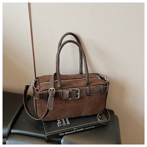 Detail of dark brown suede bucket bag featuring silver buckles and adjustable strap
