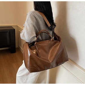 Détail du cabas en cuir marron foncé avec logo embossé et bandoulière réglable
