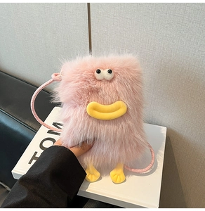 Detailed close-up of pink plush monster crossbody bag with yellow feet and big eyes
