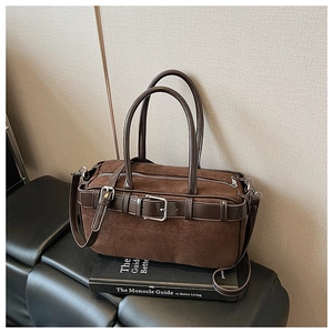 Detailed close-up of dark brown suede bucket bag with leather trim and silver metal buckle