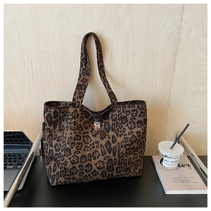 Close-up of leopard print canvas tote bag with embroidered bear badge on office desk