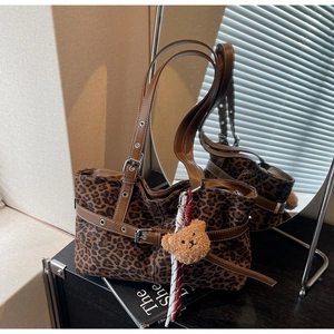 Close-up of leopard print tote bag with brown leather straps and cute plush bear charm