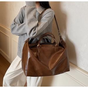 Détail du grand sac de voyage en similicuir marron avec doubles anses et étiquette