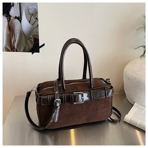 Detail of dark brown suede and leather bucket bag with silver hardware and belt strap