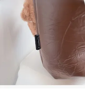 Detail of deep brown quilted down bag with shiny texture and soft plush trim details