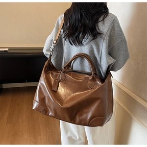 Gros plan d'un grand sac fourre-tout marron brillant avec bandoulière en tissu amovible