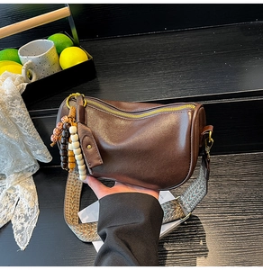 Brown leather Boston bag detail featuring colorful beaded tassel and woven strap