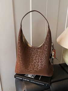 Sac fourre-tout léopard marron en daim avec pendentif bohème sur siège en cuir