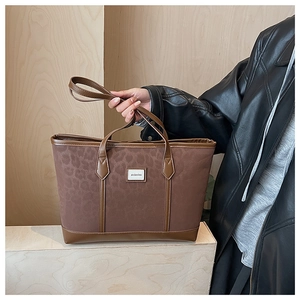 Détail du sac cabas léopard en toile avec bordures en cuir marron et logo de marque