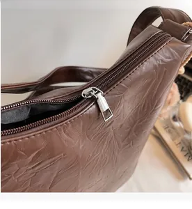 Detail of the smooth silver metal zipper on a brown textured leather shoulder bag