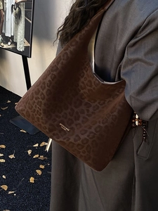 Grand sac cabas à motif léopard en cuir marron foncé porté à l'épaule par un mannequin