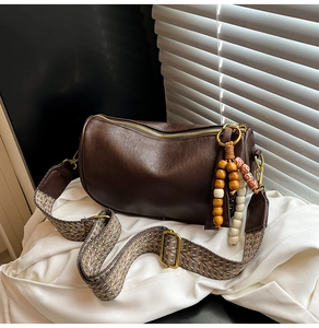 Detail of brown leather Boston bag with vintage ethnic woven strap and bead charms