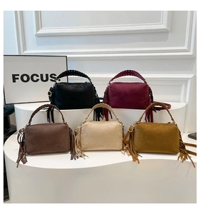 Group display of five colorful matte suede tassel handbags with braided handles in a studio