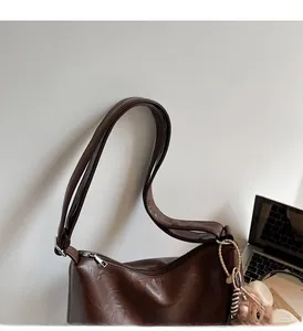 Detail of soft brown leather tote bag with sturdy shoulder strap and cute bear charm