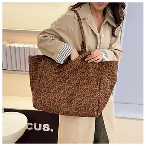 Detailed view of leopard print tote bag carried by a model in a minimal indoor setting