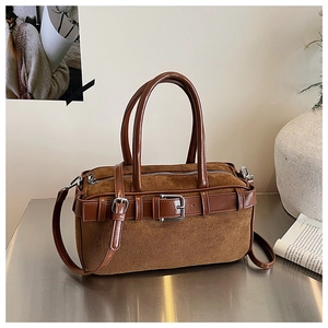 Detail view of brown suede bucket bag featuring leather straps and silver buckle accents