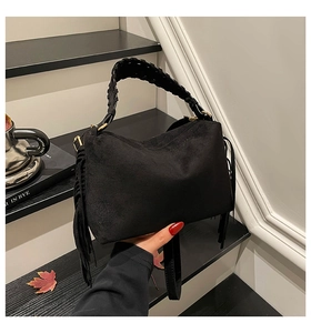 Close-up of black frosted leather pillow bag with long fringe and braided handle detail