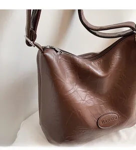 Close-up of brown tote bag showing crinkled leather texture and silver zipper detail
