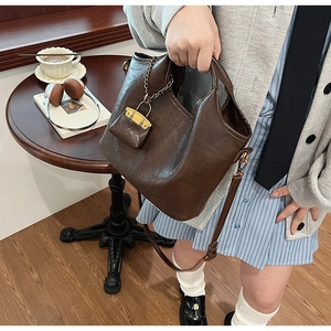 Sac seau vintage café foncé avec petit porte-monnaie sur une table en bois élégante