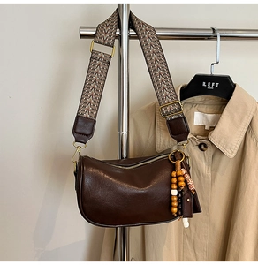 Detail of dark brown Boston bag with ethnic woven strap and leather tassel charm