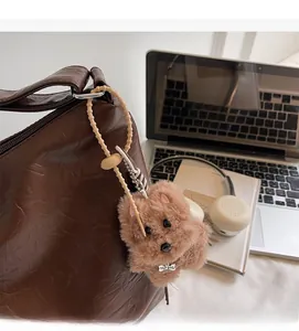 Detail of plush dog keychain with TOP DOG bone tag on a brown leather tote bag