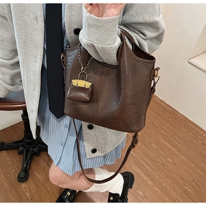 Detail of vintage brown bucket bag with mini coin purse charm and leather strap