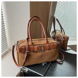 Detail view of brown suede bucket bag with leather belt buckle and silver hardware