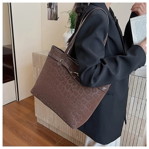 Détail du sac cabas léopard avec bordure en cuir et boucle métallique sur la bandoulière