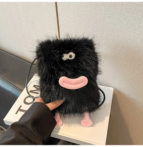 Detail of a black plush crossbody bag with cartoon monster eyes and pink foot accents