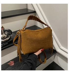 Detail of dark brown suede pillow bag with fringe edges and woven leather handles