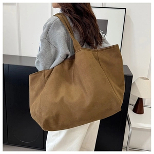 Detail of a large leopard print tote bag in brown suede fabric shown on shoulder
