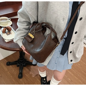 Sac seau en cuir marron avec détail de chaîne dans un décor de café décontracté