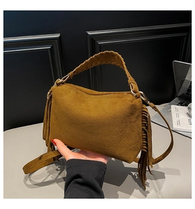 Close-up of brown frosted suede handbag with fringed tassels and woven handle detail