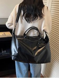 Grand sac fourre-tout en cuir brillant noir pour voyage et fitness dans un décor minimaliste